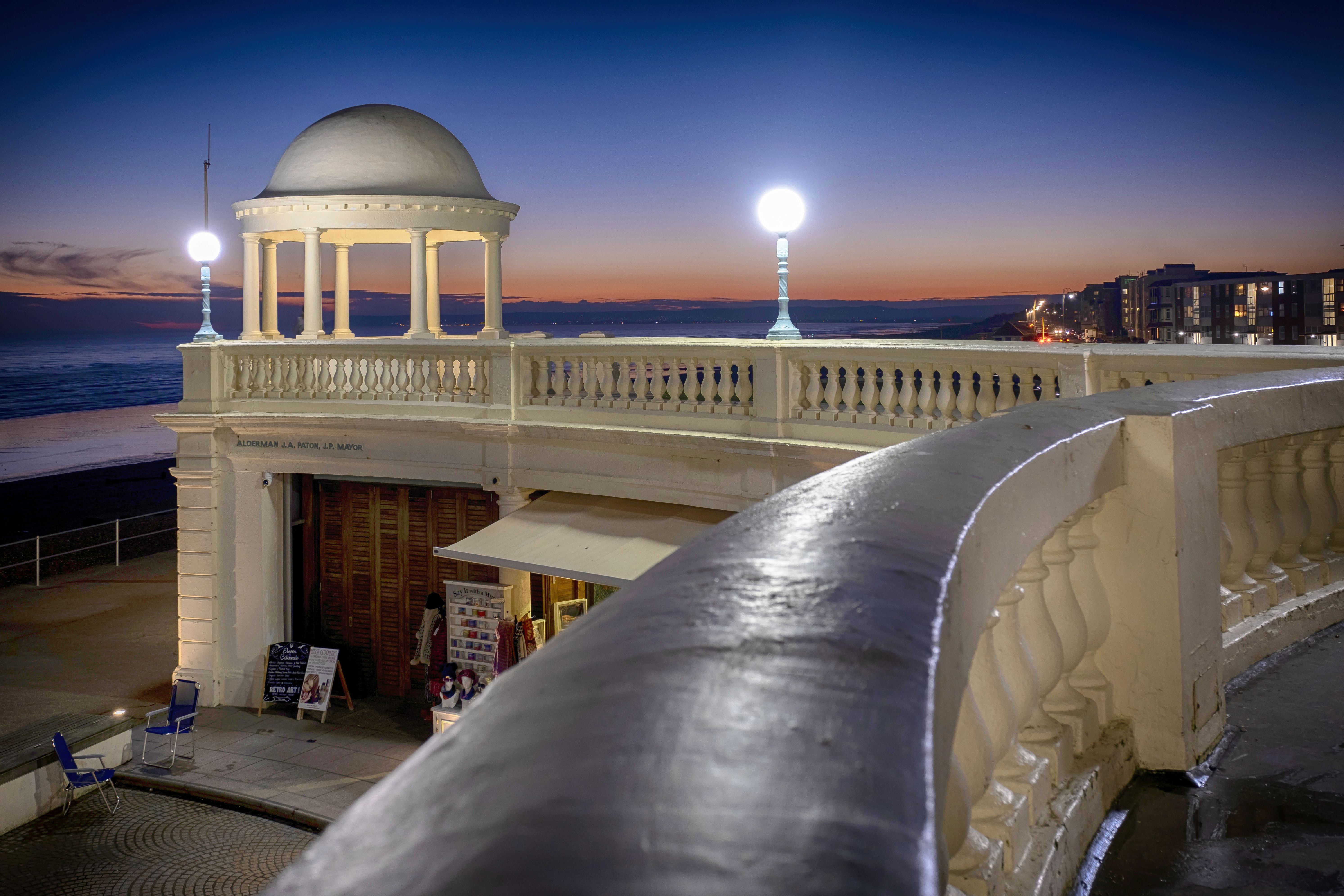 photograph of twilight sky with promenade shelter and white wall